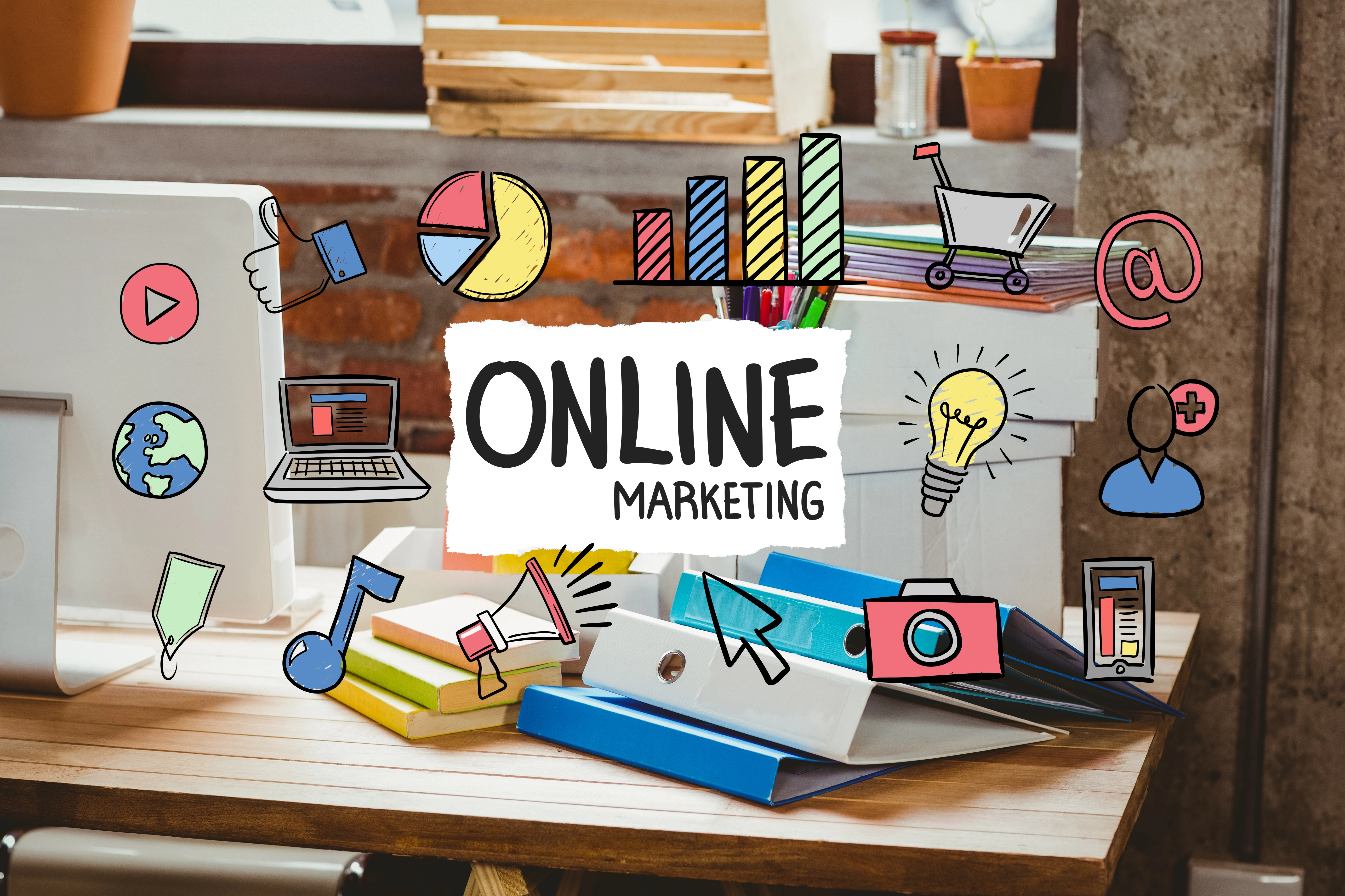 A desktop with binders, a laptop, and various icons related to online marketing, including charts, a light bulb, a megaphone, and a camera, with the words "ONLINE MARKETING" prominently displayed. Ideal for showcasing a content marketing agency.