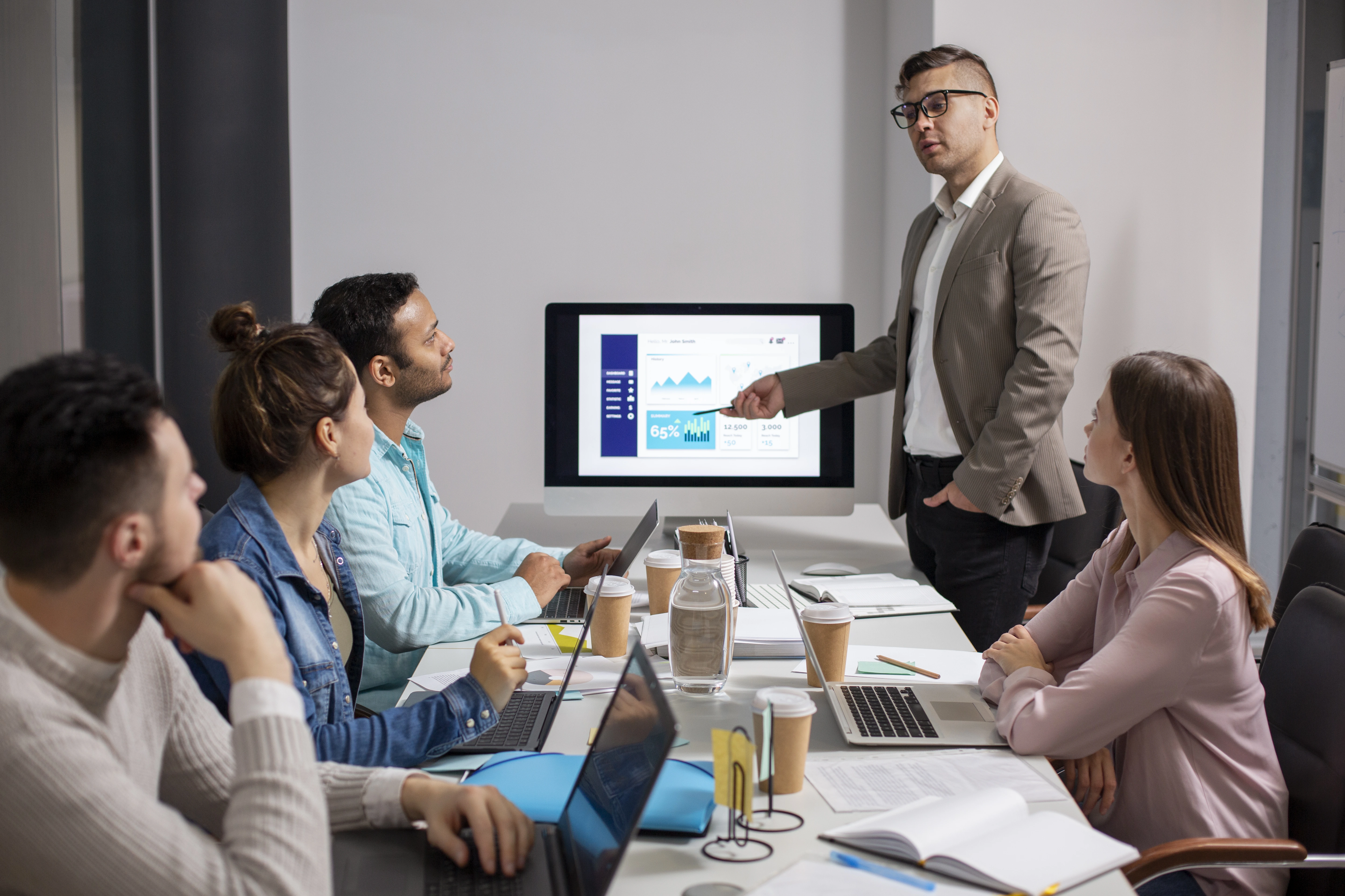 A group of professionals in a meeting, with one person presenting data on a screen, ideal for showcasing a PPC agency discussing campaign results and strategies.
